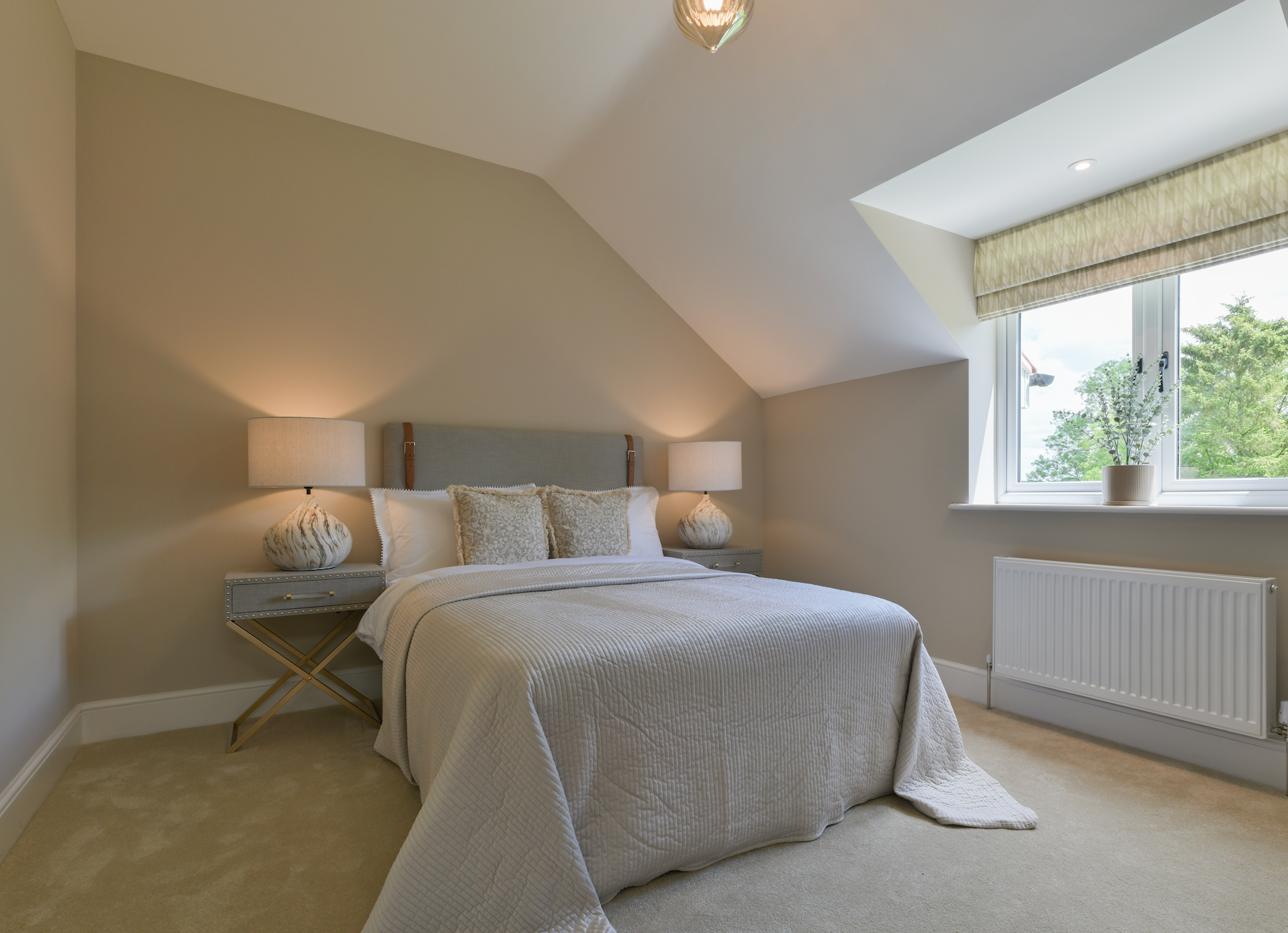 Neatly arranged bedroom with a bed, lamps, and a window.