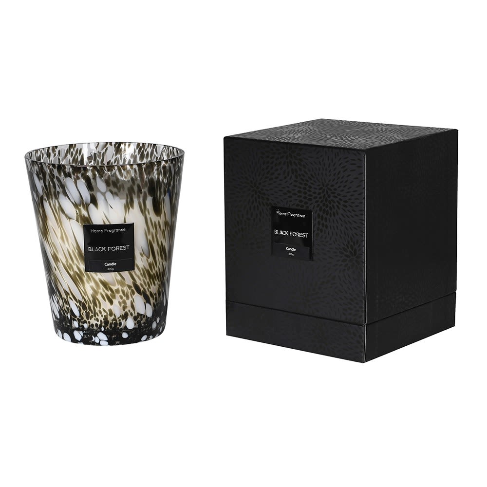 Decorative candle with black and white pattern next to its packaging box on a white background