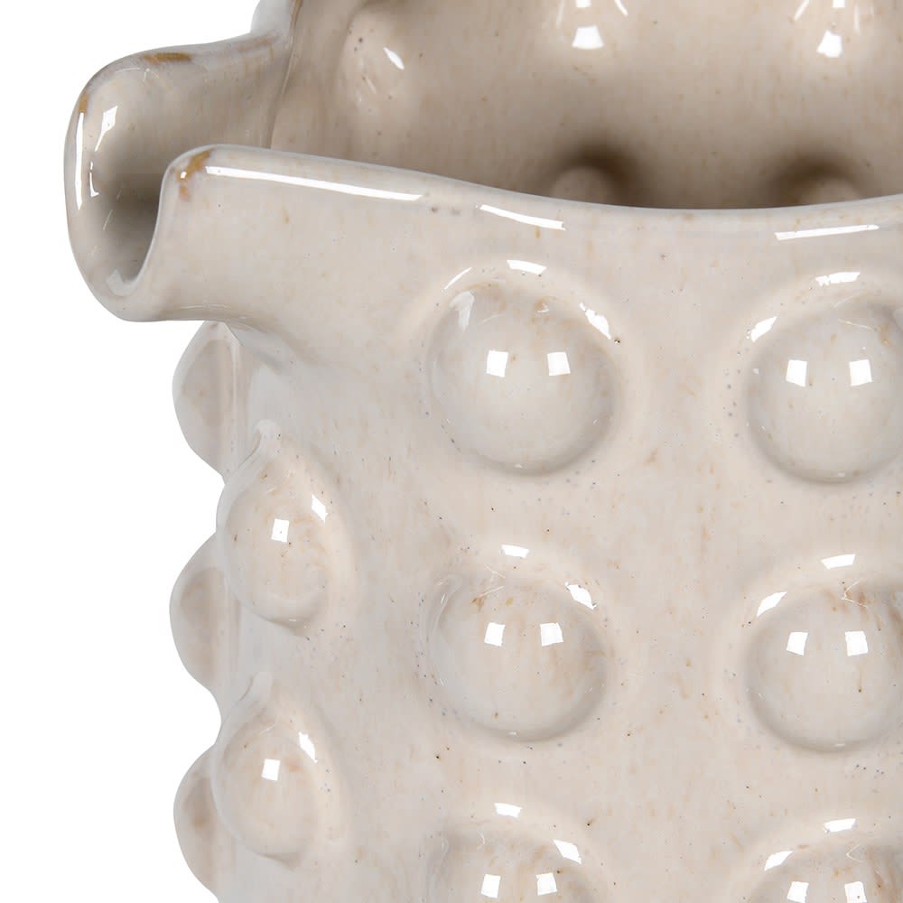 Close-up of a textured ceramic vase with circular patterns on a white background