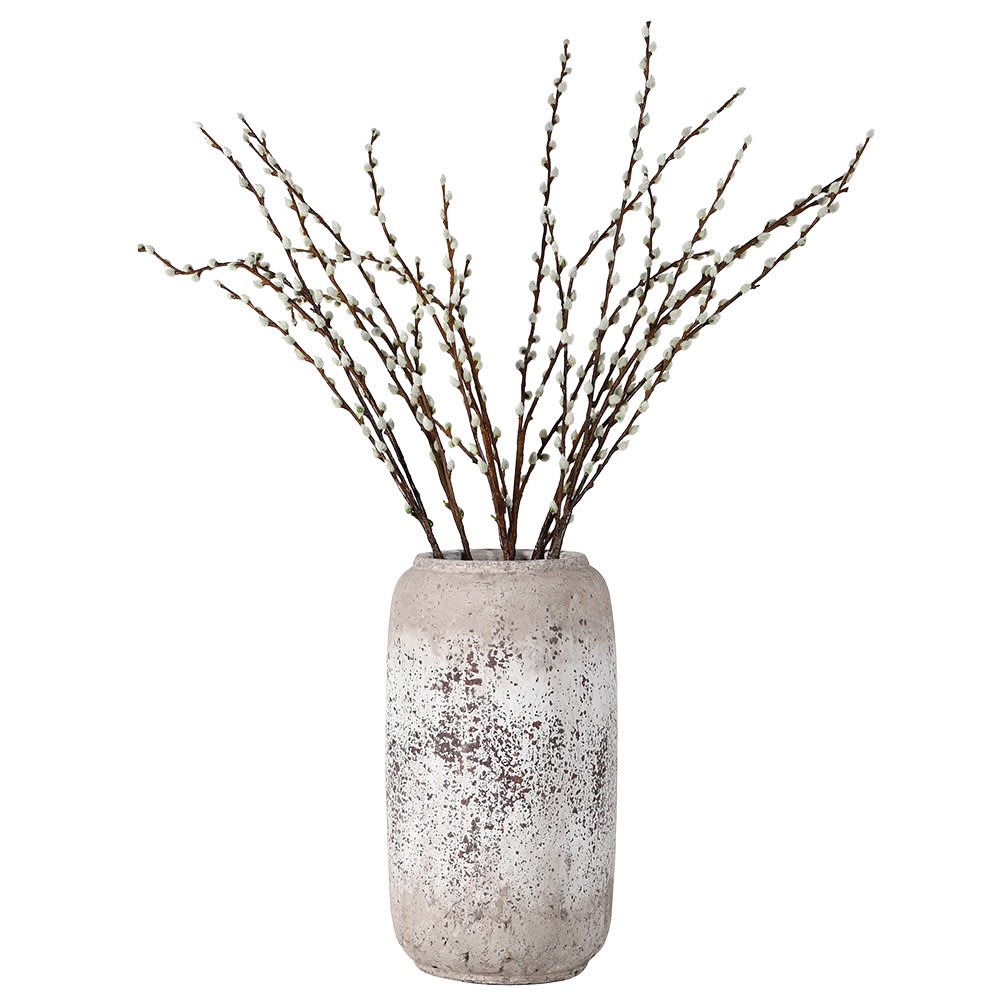 Decorative vase with textured surface holding dried branches on a white background